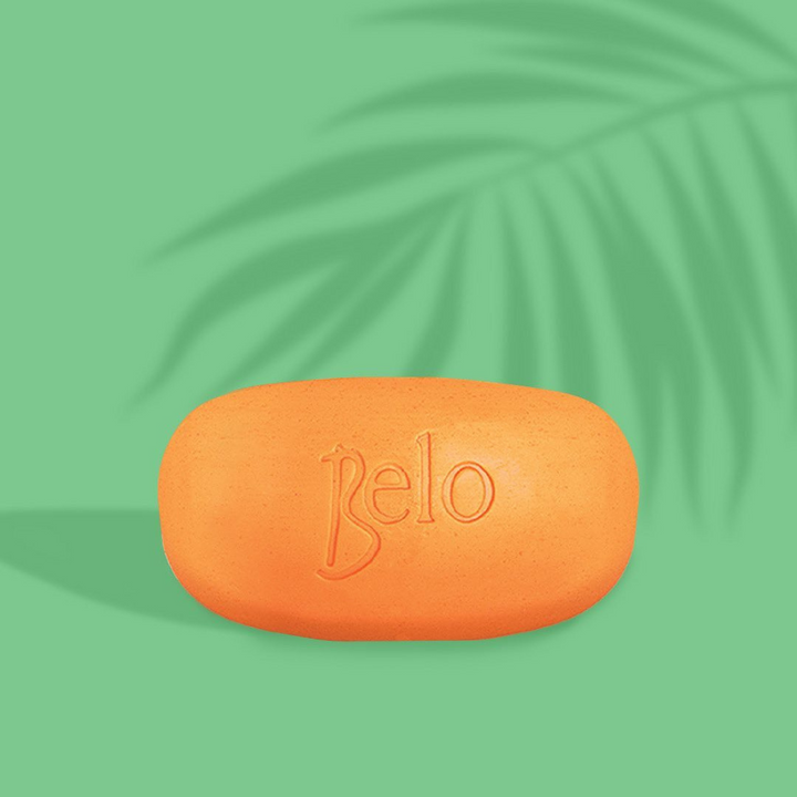 Orange bar of soap with 'Belo' branding on a green background with palm leaf shadows