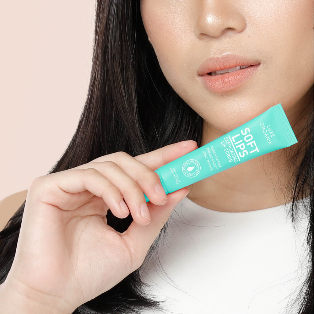 Person holding a tube of 'Soft Lips' product against a beige background