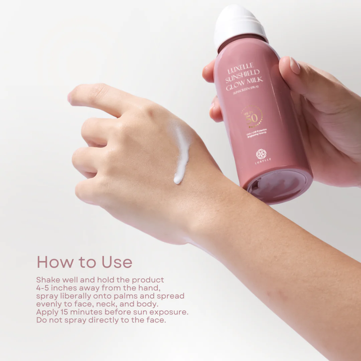 Person applying pink sunscreen spray to arm with text on how to use it. Luxelle Sunshield Glow Milk Sunscreen Spray