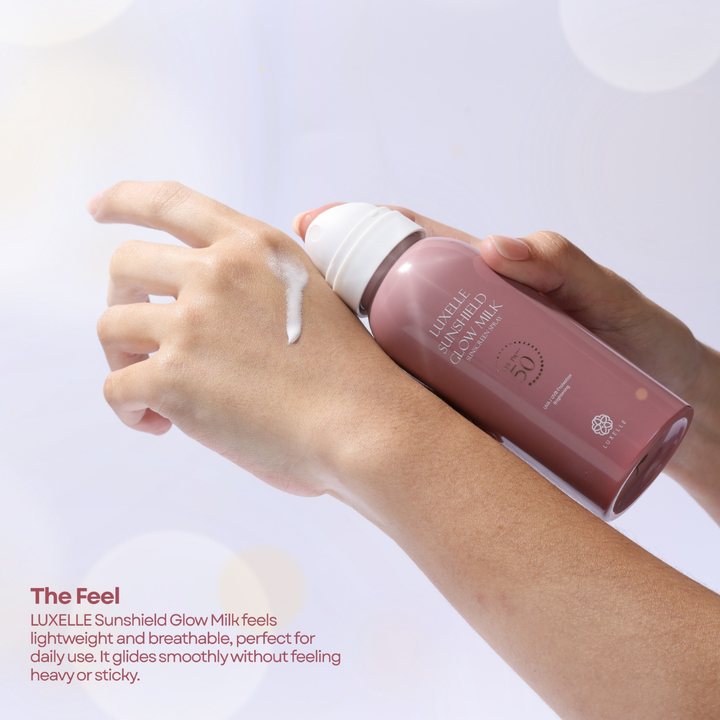 Person applying Luxelle Sunshield Glow Milk to their arm with a white background Luxelle Sunshield Glow Milk Sunscreen Spray