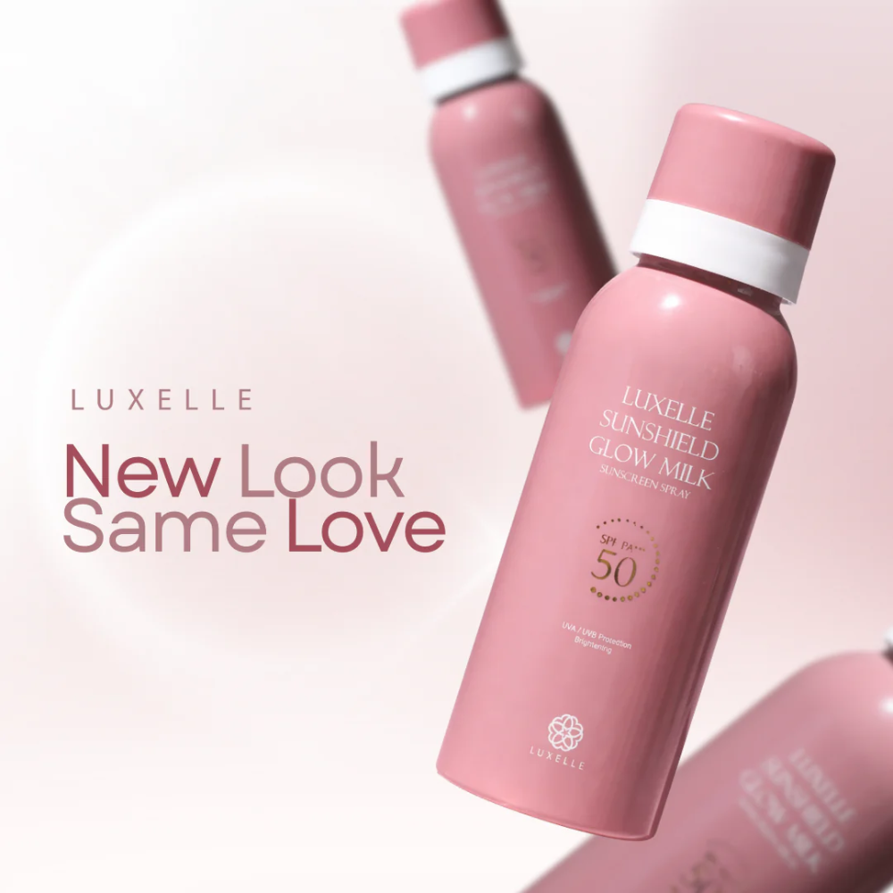 Pink sunscreen bottle with white cap on a light pink background, featuring Luxelle branding. Luxelle Sunshield Glow Milk Sunscreen Spray