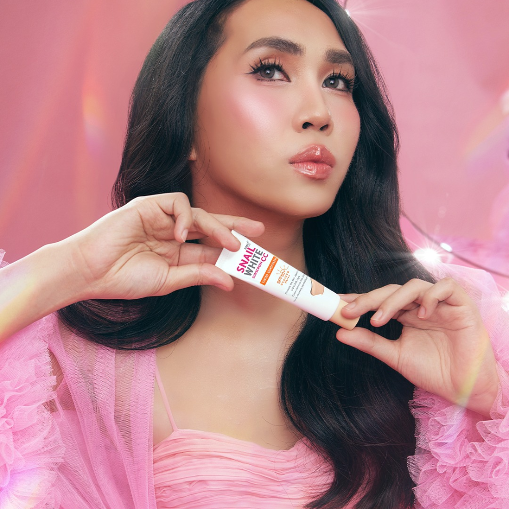 Woman holding a skincare product with a pink background