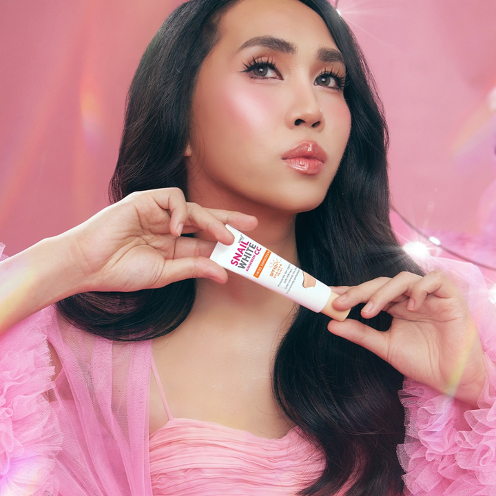 Woman holding a skincare product with a pink background