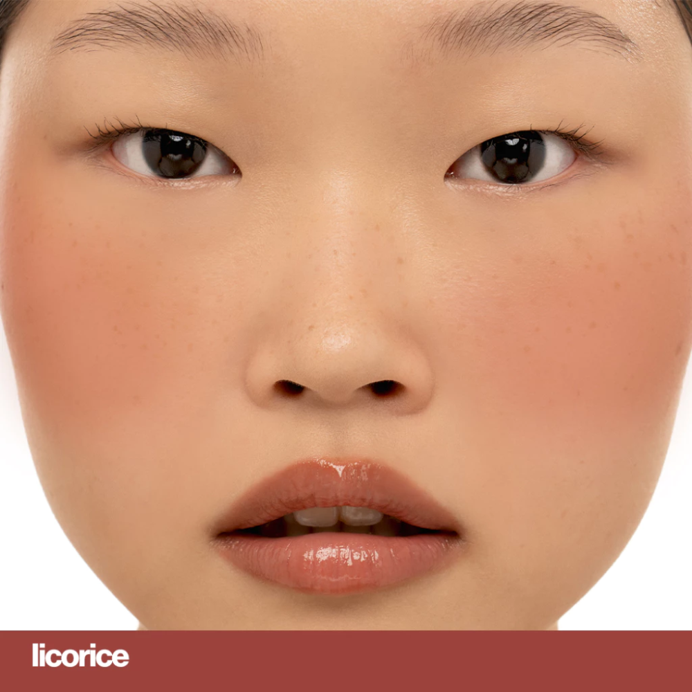 Close-up of a person's face with a focus on the lips, showing a shade labeled 'licorice'. Sunnies Face Blush On - Licorice