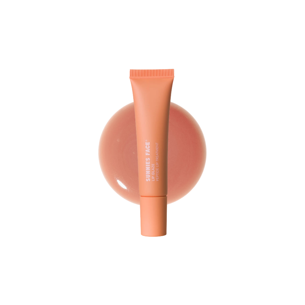 Peach-colored cosmetic tube on a peach-colored sphere against a white background Sunnies Face Lip Glaze - a peptide lip treatment Dolly