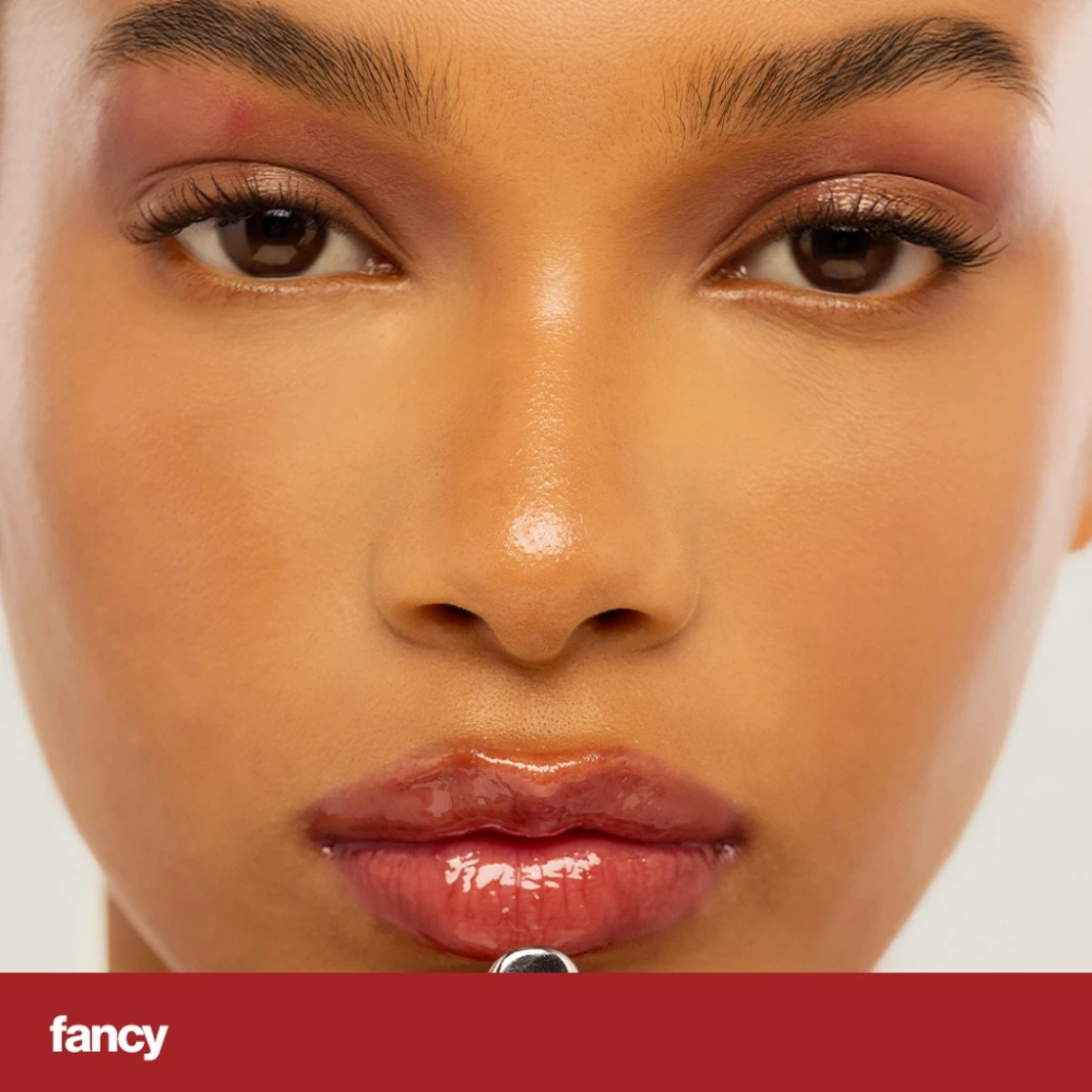 Close-up of a person's face with a neutral background and 'fancy' shade. Sunnies Face Lip Glaze - a peptide lip treatment