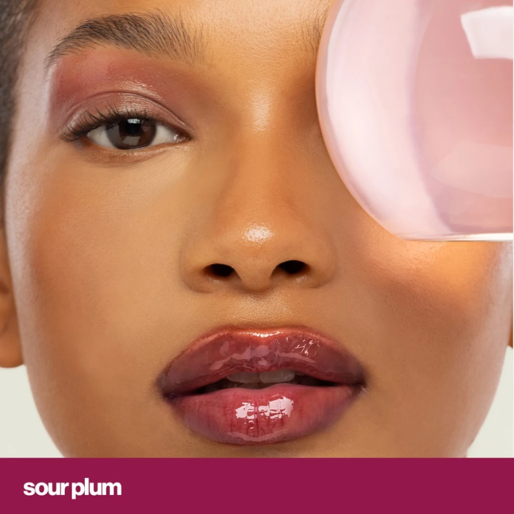 Close-up of a person wearing a glossy lip color with 'sourplum' text at the bottom. Sunnies Face Lip Glaze - a peptide lip treatment Sour Plum